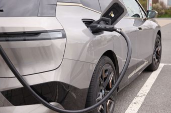 Nahaufnahme eines Autos, das auf einem Parkplatz elektrisch aufgeladen wird.